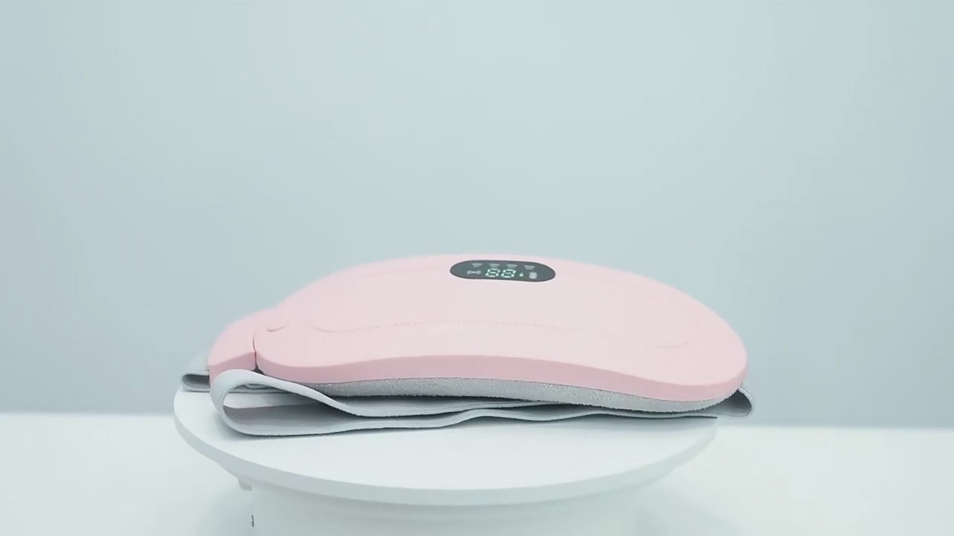 Ceinture chauffante SwissTouch rose en démonstration, écran digital affichant la température et sangle grise ajustable